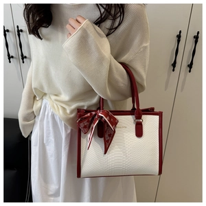 Detail of red and white tote bag with crocodile pattern and red polka dot silk scarf