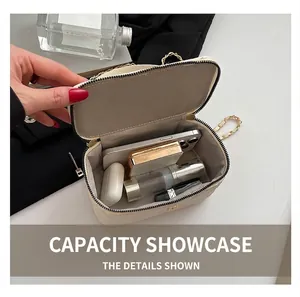 Interior view showing the capacity of this beige quilted vanity case with chain strap