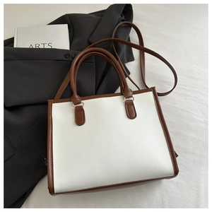 Close-up of minimalist trapezoid handbag with brown leather trim and ribbon detail