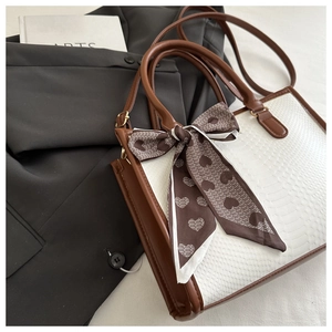 Close-up of white faux snake pattern tote with brown leather trim and heart print scarf