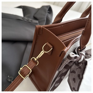 Detail view of brown faux leather handbag with heart print ribbon and gold hardware