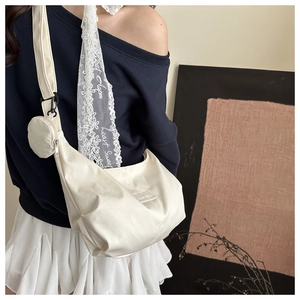 Détail d'un sac à bandoulière en nylon crème avec une petite pochette ronde