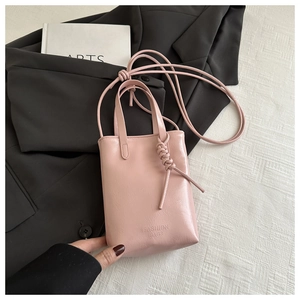Détail du sac cabas rose brillant avec gravure de mode et poignée à nœud tressé