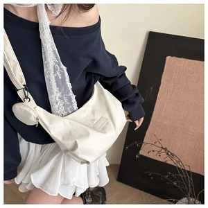 Detail of white canvas crossbody bag featuring the small detachable coin pouch and strap label