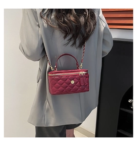 Close-up of wine red quilted mini crossbody bag with gold floral clasp and metal chain