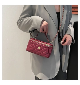 Close-up of quilted burgundy box bag with gold floral logo and woven chain strap