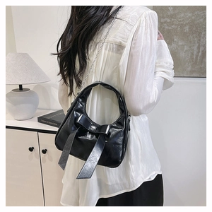 Detail of black leather hobo bag featuring a large bow and silver chain strap