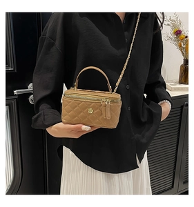 Detail of khaki quilted crossbody bucket bag featuring golden flower charm and chain strap