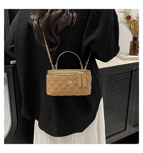 Close-up of khaki quilted leather crossbody bag with golden camellia and chain strap
