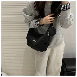 Woman wearing a black nylon crescent shoulder bag with a small detachable coin purse