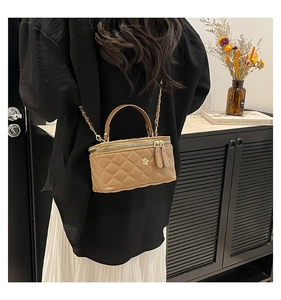 Detail of khaki quilted crossbody bag with flower buckle and chain strap on a model