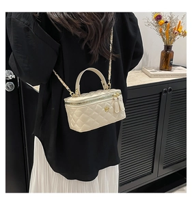 Detailed view of cream quilted box bag with gold floral clasp and chain strap