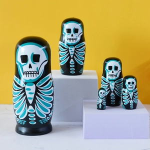 Five-piece skull pattern wooden nesting dolls on geometric blocks with yellow backdrop