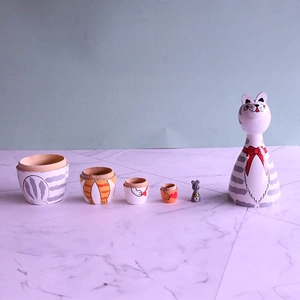 Detail showing layers of a hand-painted wooden cat nesting doll set and tiny mouse toy
