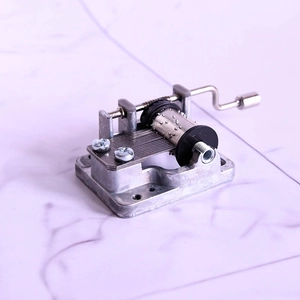 Detail of silver metal hand-crank music box movement with cylinder and comb components