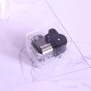 Transparent acrylic music box with visible silver mechanical movement on marble background