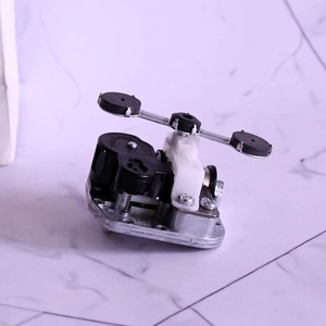 Mechanical wind-up music box movement with rotating balancer on marble background