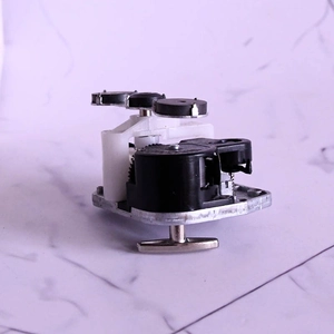 Mechanical wind-up music box movement with white plastic gears and metal T-shaped key