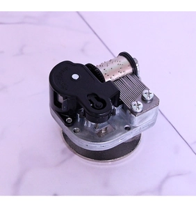 Mechanical music box movement with metal comb and cylinder on white marble background