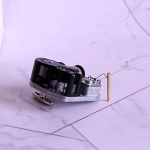 Detailed view of music box movement with brass rod brake and black plastic housing