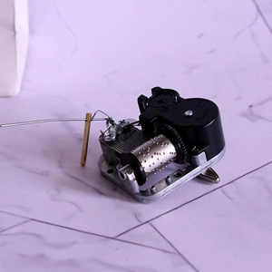 Detailed macro view of DIY music box movement mechanism with metal cylinder and copper brake