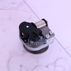 Mechanical music box movement with rotating circular base and silver metal components
