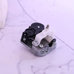 Mechanical wind-up music box movement with rotating cylinder and zinc alloy base component