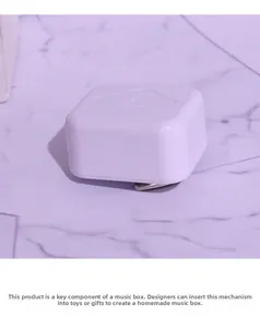 Close-up of DIY mechanical music box movement with white plastic case and metal winder