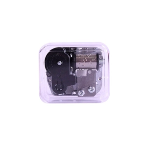 Transparent musical box with silver mechanical movement and visible gears on white backdrop