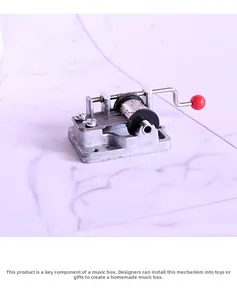 Close-up of DIY hand-crank music box movement with a red ball handle and metal gears