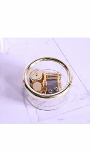 Detailed top view of gold-plated music box movement within transparent round casing