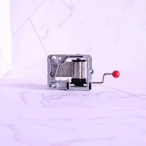 Mini hand-cranked musical box mechanism in silver zinc alloy with red ball handle