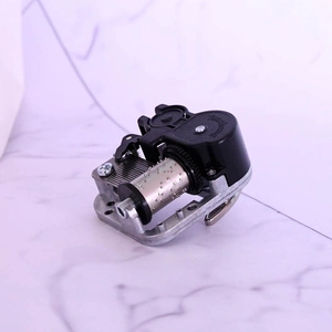 Detailed top view of a mechanical music box movement with silver base and black stop lever