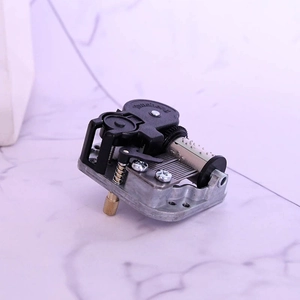 Mechanical 18-note wind-up music box movement with silver metal base and golden key