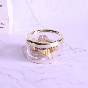 Klare runde Spieluhr mit goldenem Mechanikwerk auf lila Marmorhintergrund
