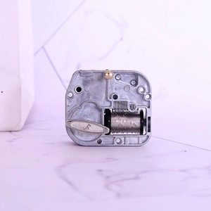 Mechanical 18-note music box movement with winding key and metallic cylinder on marble