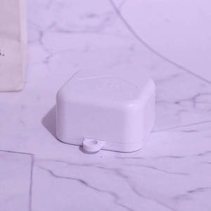 Close-up of a white mini mechanical musical box plastic case on marble background