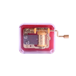 Mechanical hand-crank music box with golden movement and transparent purple plastic case