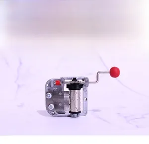 Close-up of 18-note hand-crank music box mechanism with metal cylinder and red handle