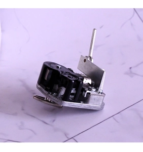 Close-up of wind-up music box movement with gears and crank on marble background