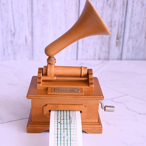 Detailed macro view of vintage wooden gramophone music box with hand crank and paper strip