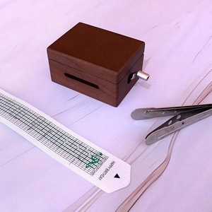 Détail de boîte à musique DIY en bois avec bande papier et outil sur tissu violet