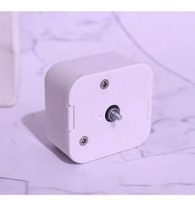 Close-up of white plastic music box shell with central metal threaded output shaft