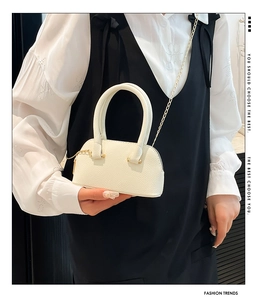 Close-up of white lychee texture shell bag with golden chain strap and leather handle