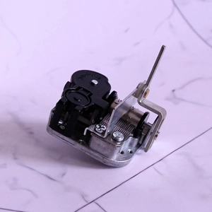 Detailed top view of a mechanical 18-note music box movement on a marble surface