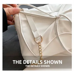 Detail of the white shoulder bag featuring a large bow and gold metal chain strap connector