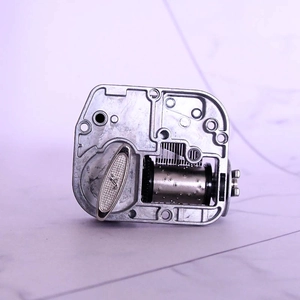 Mechanical wind-up music box movement in silver metal with precision internal gears