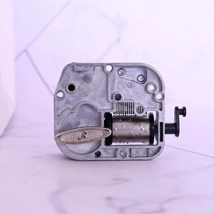 Mechanical wind-up music box movement made of durable metal with a hand crank handle
