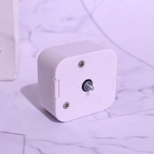 Mechanical music box movement with white plastic case and central threaded metal spindle
