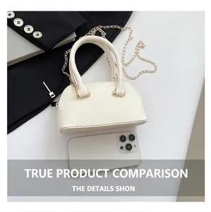 Mini white pebble leather shell bag with gold chain strap shown next to a smartphone